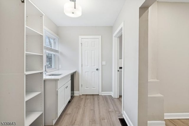 interior space with baseboards, a sink, and light wood-style floors