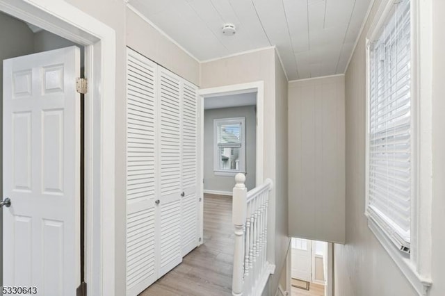 hall with ornamental molding, light wood-type flooring, and an upstairs landing