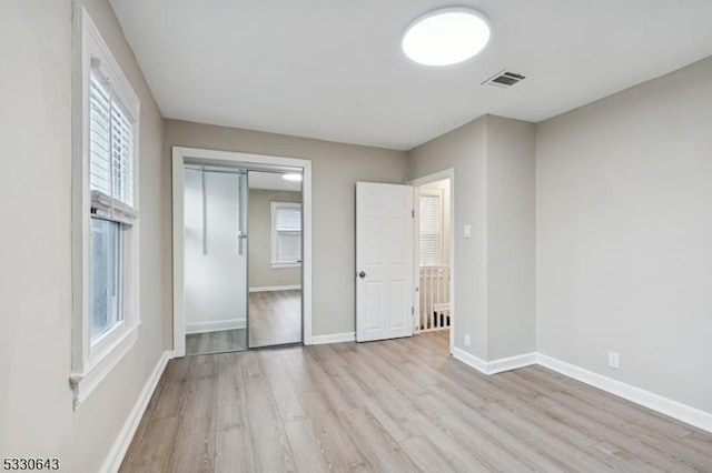 unfurnished bedroom with a closet, light wood-type flooring, visible vents, and baseboards