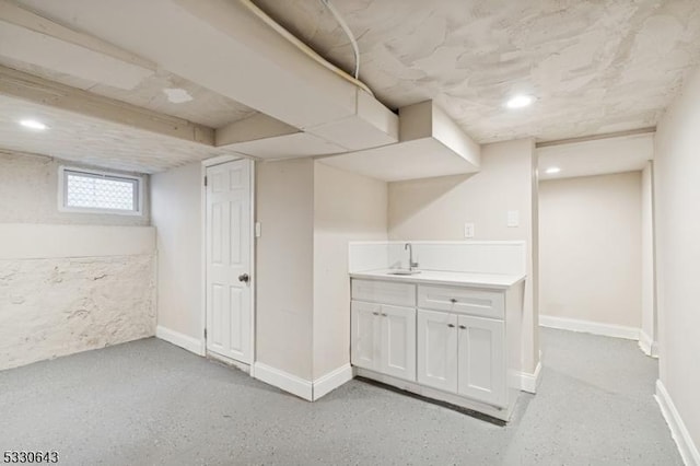 basement featuring a sink and baseboards