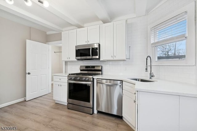 kitchen featuring tasteful backsplash, appliances with stainless steel finishes, a sink, and beamed ceiling