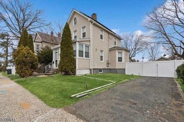 view of side of property featuring a chimney, a lawn, entry steps, a gate, and fence