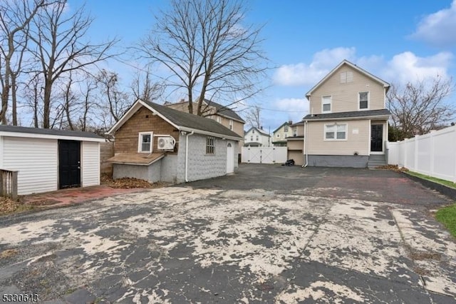 view of home's exterior with entry steps, driveway, an outdoor structure, and fence