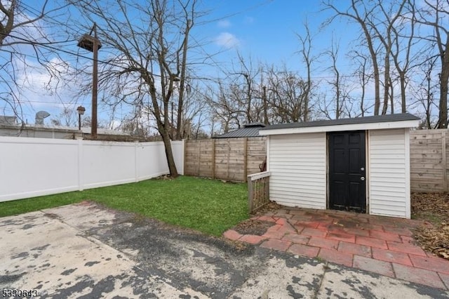 view of yard with a patio area, a fenced backyard, a storage unit, and an outbuilding