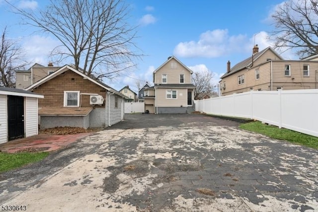 exterior space featuring driveway, fence, and an outdoor structure