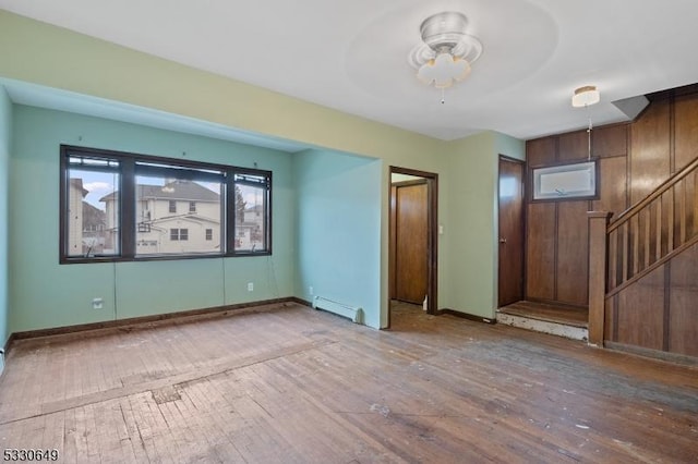 unfurnished room with ceiling fan, hardwood / wood-style flooring, and a baseboard heating unit