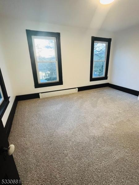 carpeted empty room featuring baseboard heating