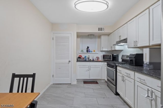 kitchen with white cabinets, decorative backsplash, stainless steel appliances, and dark stone countertops