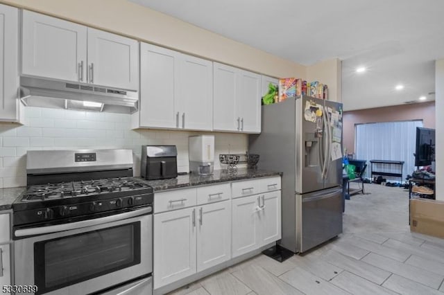 kitchen featuring white cabinets, decorative backsplash, appliances with stainless steel finishes, and dark stone counters