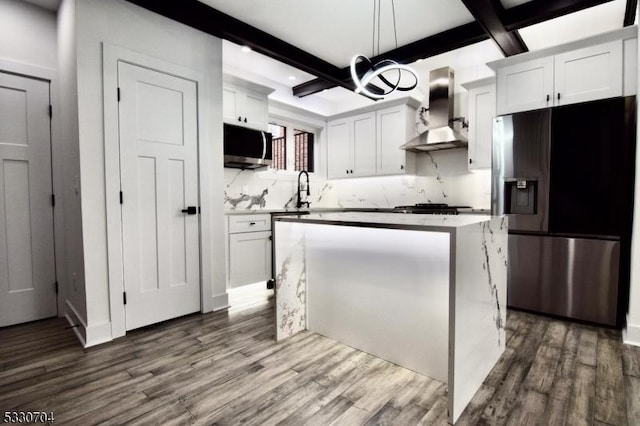 kitchen featuring white cabinets, beamed ceiling, stainless steel appliances, and wall chimney exhaust hood