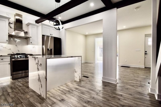 kitchen featuring appliances with stainless steel finishes, a center island, wall chimney exhaust hood, white cabinets, and beamed ceiling