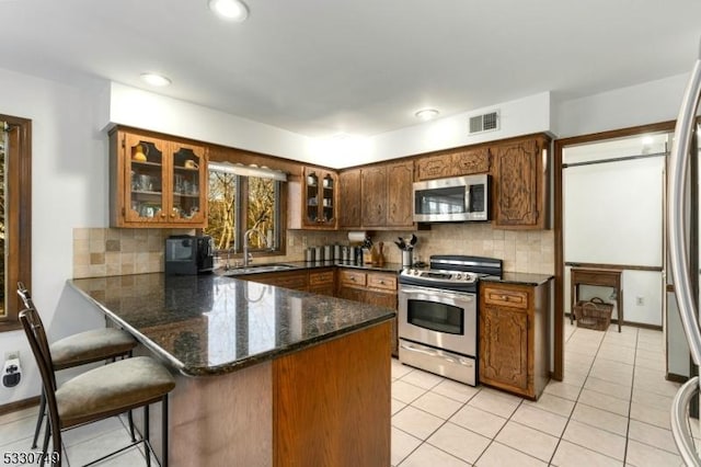 kitchen with kitchen peninsula, decorative backsplash, sink, and stainless steel appliances