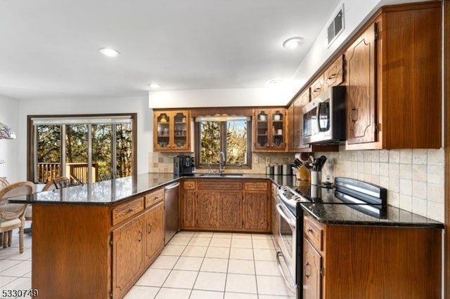 kitchen with sink, decorative backsplash, dark stone countertops, kitchen peninsula, and stainless steel appliances