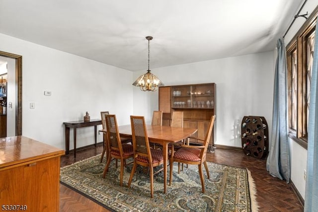 dining area featuring dark parquet floors and a notable chandelier