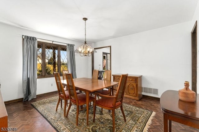 dining space featuring dark parquet floors and an inviting chandelier