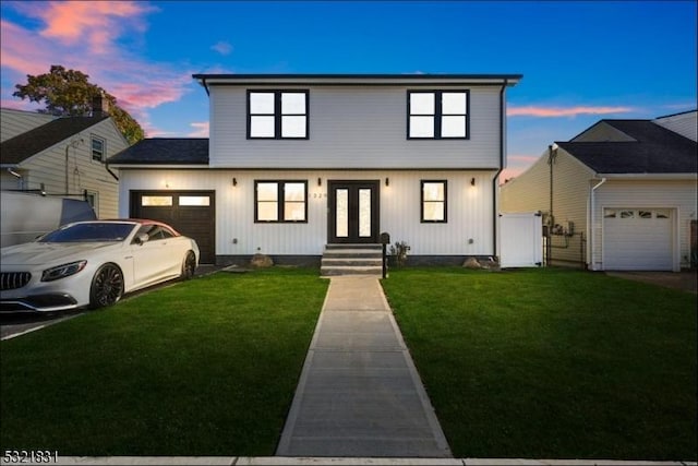 view of front of property with a lawn, a garage, and french doors