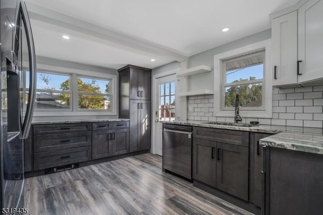 kitchen with backsplash, sink, light stone countertops, appliances with stainless steel finishes, and dark brown cabinetry