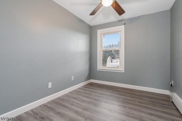 spare room featuring wood-type flooring, a baseboard radiator, and ceiling fan