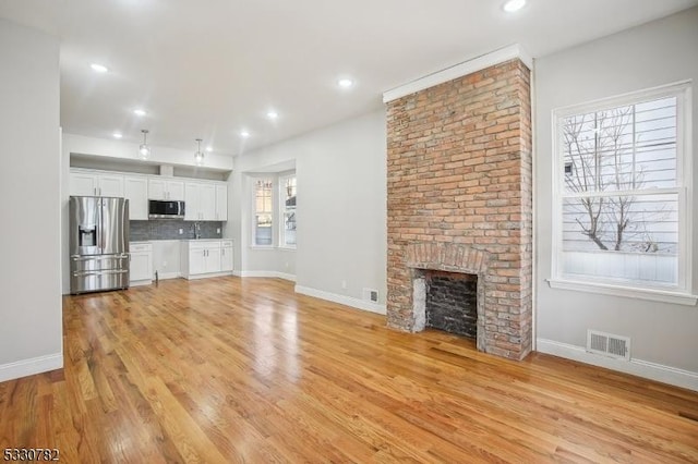 unfurnished living room featuring a fireplace and light hardwood / wood-style floors