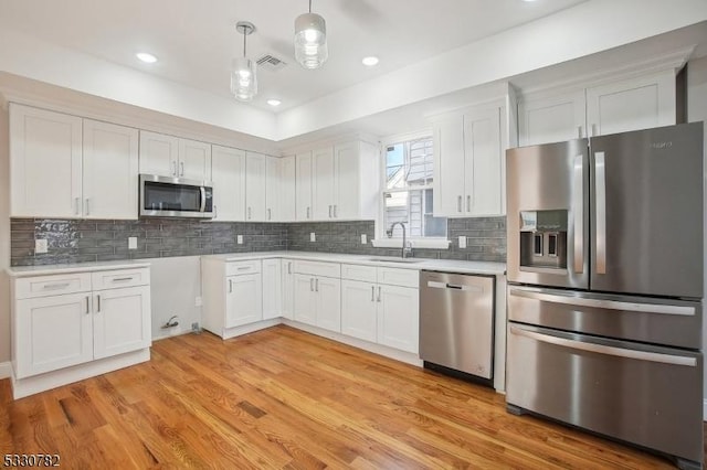 kitchen with hanging light fixtures, white cabinets, sink, and stainless steel appliances