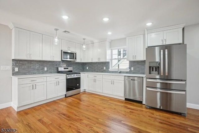 kitchen featuring stainless steel appliances, pendant lighting, white cabinetry, and sink