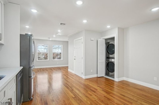 interior space with stacked washing maching and dryer and light hardwood / wood-style floors