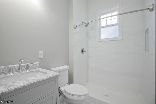 bathroom with toilet, vanity, and a tile shower