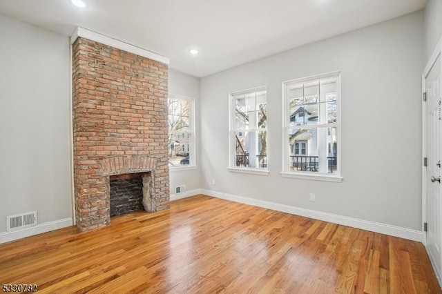 unfurnished living room with a brick fireplace and light hardwood / wood-style floors