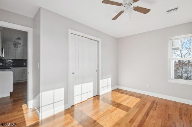 unfurnished bedroom with ceiling fan, a closet, and wood-type flooring