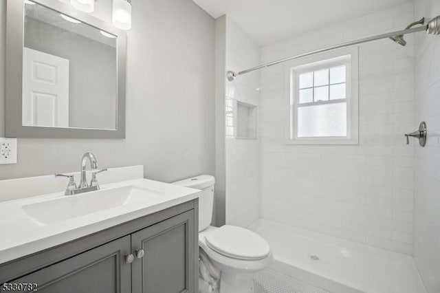 bathroom with toilet, vanity, and a tile shower