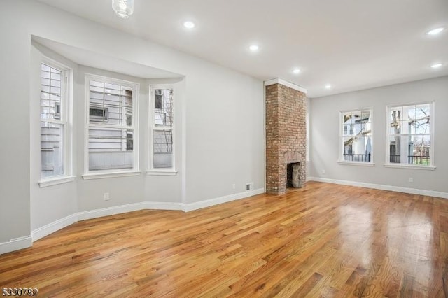 unfurnished living room featuring light hardwood / wood-style floors, a fireplace, and plenty of natural light