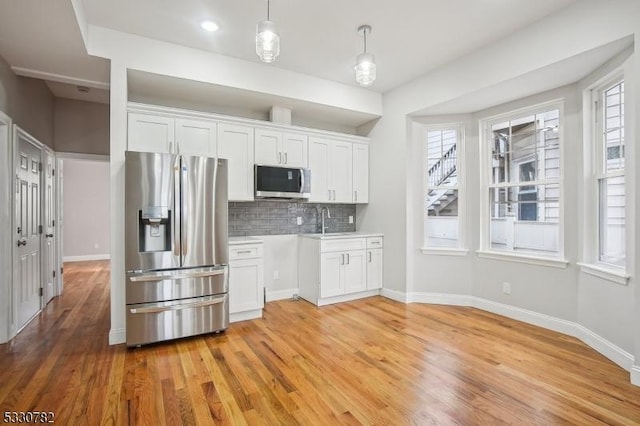 kitchen with white cabinetry, stainless steel appliances, backsplash, pendant lighting, and sink