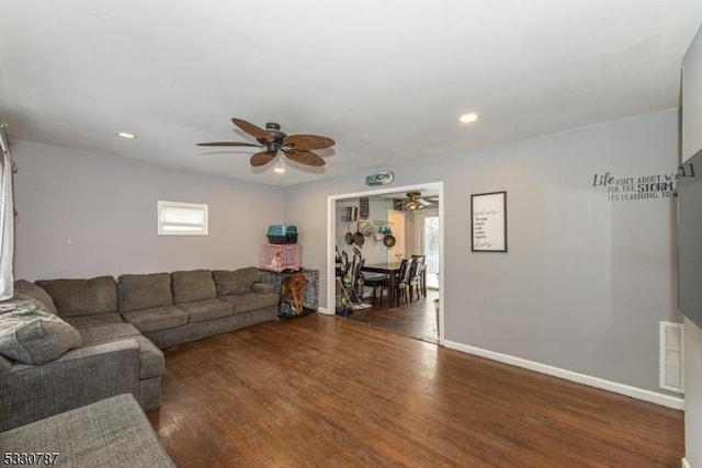 living room with ceiling fan and dark wood-type flooring