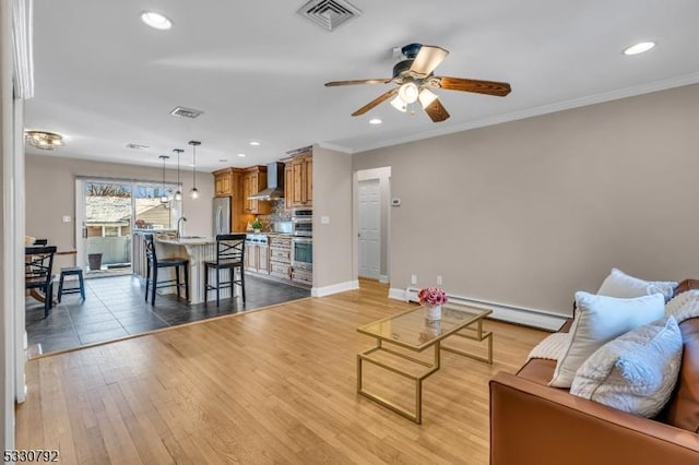 living room with a baseboard radiator, crown molding, ceiling fan, and light hardwood / wood-style floors