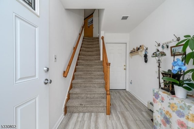 staircase with hardwood / wood-style floors and a baseboard radiator