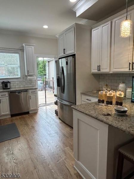 kitchen featuring light stone countertops, stainless steel appliances, white cabinetry, and hanging light fixtures