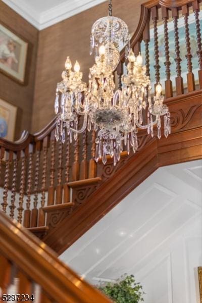 staircase featuring a notable chandelier and ornamental molding