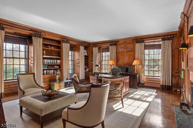 sitting room with hardwood / wood-style floors, built in shelves, wood walls, and crown molding