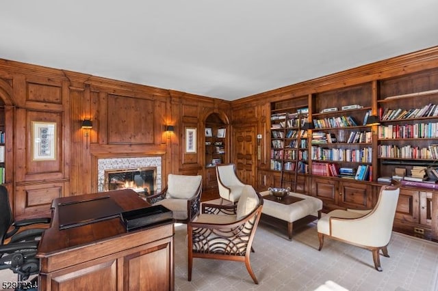 living area featuring built in shelves, wood walls, and light colored carpet