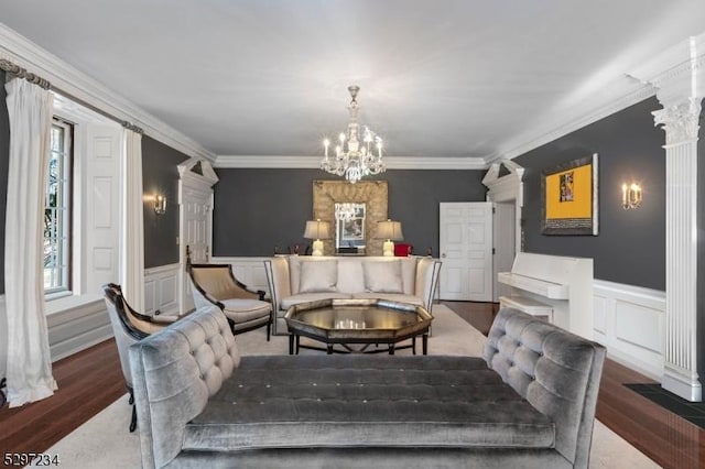 interior space featuring ornate columns, an inviting chandelier, wood-type flooring, and ornamental molding