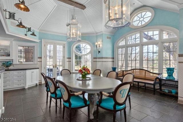 dining room with french doors, a notable chandelier, wood ceiling, tile walls, and ornamental molding