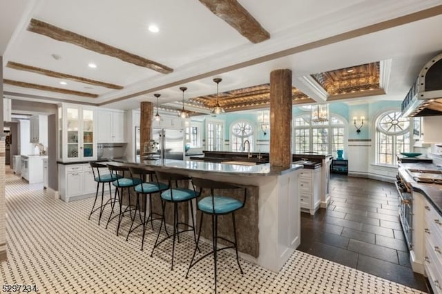 kitchen featuring white cabinetry, a center island, stainless steel appliances, a kitchen breakfast bar, and decorative light fixtures