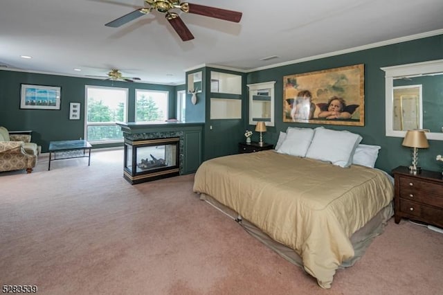 bedroom featuring ceiling fan, a multi sided fireplace, carpet floors, and ornamental molding