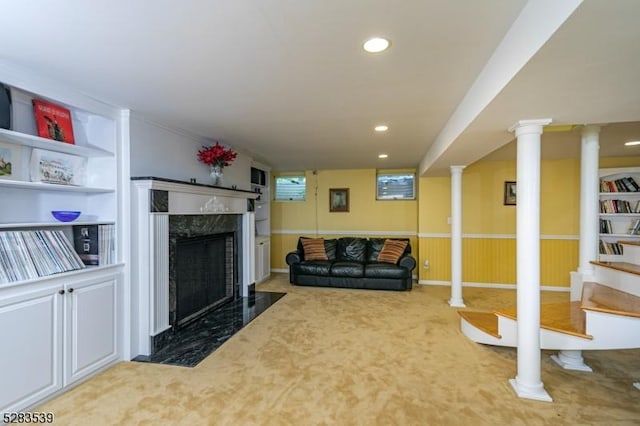 carpeted living room with a fireplace, built in shelves, and wood walls