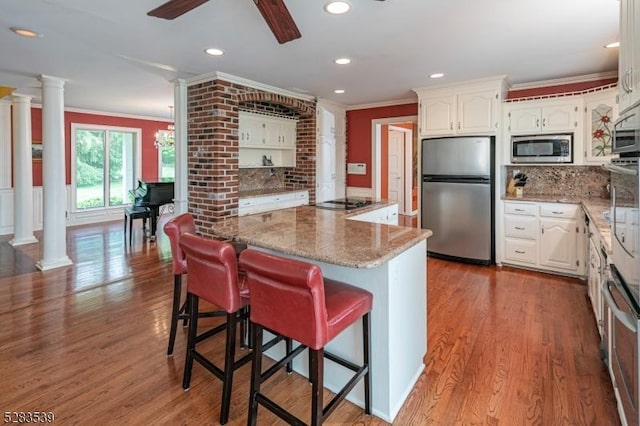 kitchen with white cabinetry, stainless steel appliances, and decorative columns