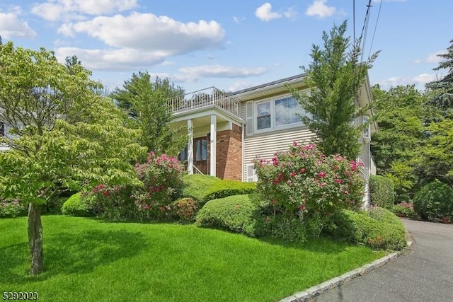 view of side of property with a yard and a balcony