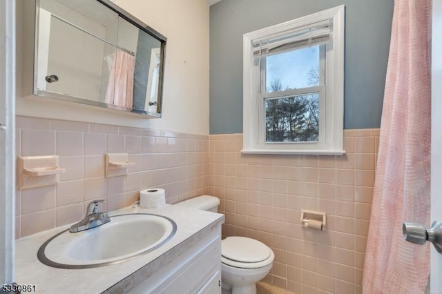 bathroom featuring vanity, tile walls, and toilet