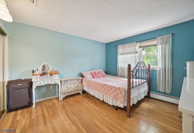 bedroom with light wood-type flooring and a baseboard radiator