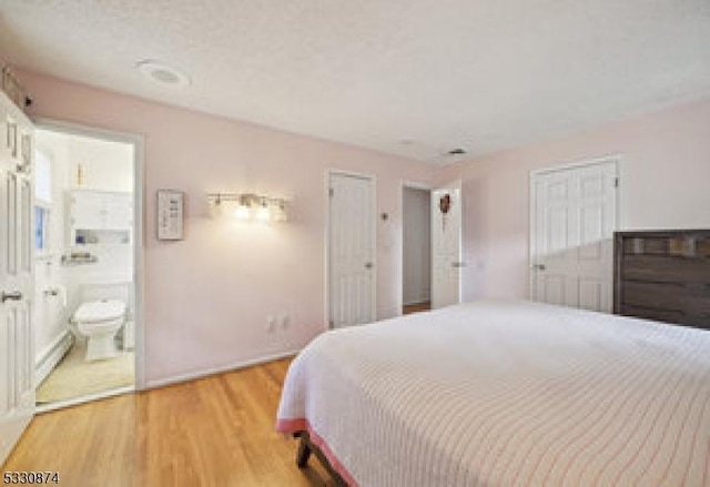 bedroom with connected bathroom and light hardwood / wood-style flooring