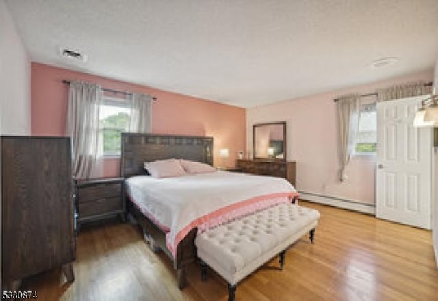 bedroom with hardwood / wood-style flooring and baseboard heating